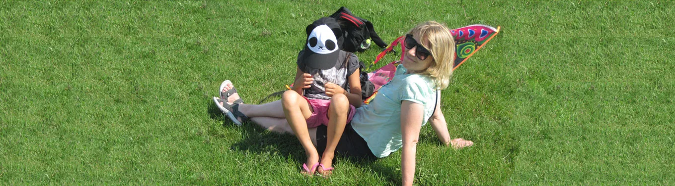 An adult and a child sitting together on a grassy hillside